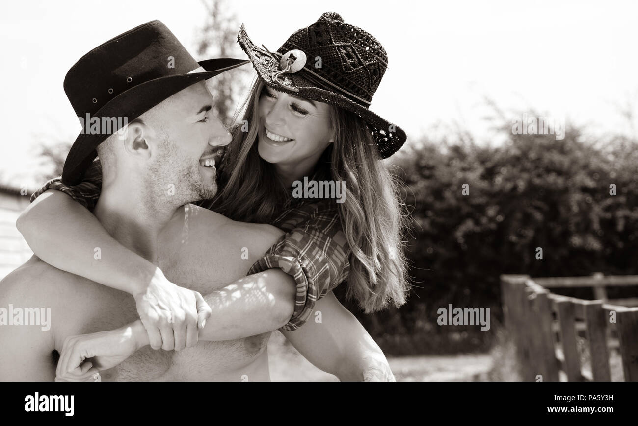 Cowboy et Cowgirl rire et sourire comme il porte sur le dos, à la fois  porter un chapeau sur ranch Photo Stock - Alamy