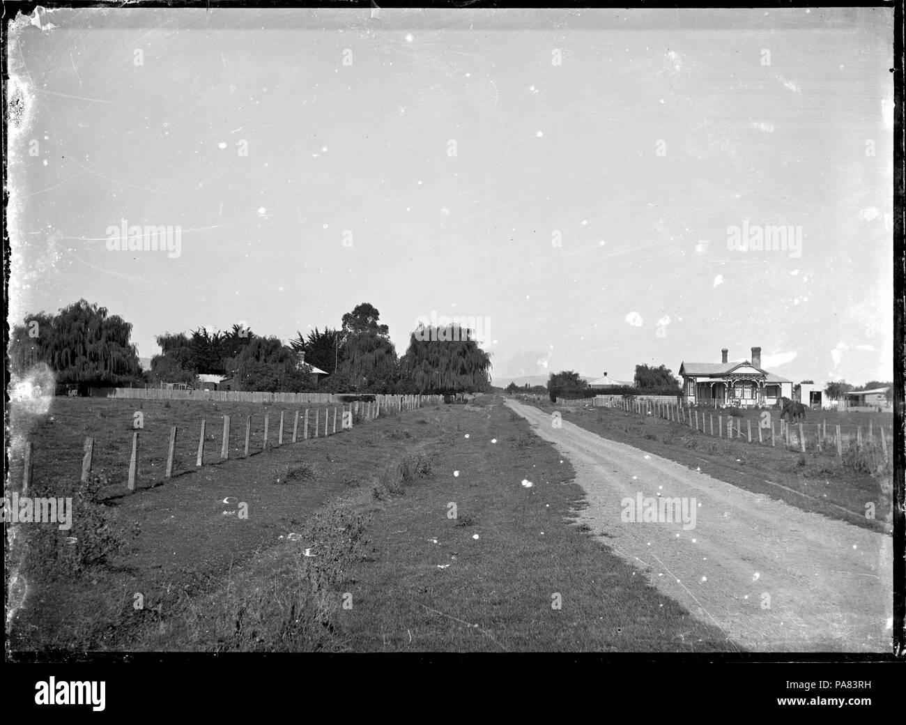 Scène 56 pays avec une route entre deux champs, et avec deux maisons, une en partie visible sur la gauche, et un bungalow avec vérandas sur le droit ATLIB 324450 Banque D'Images
