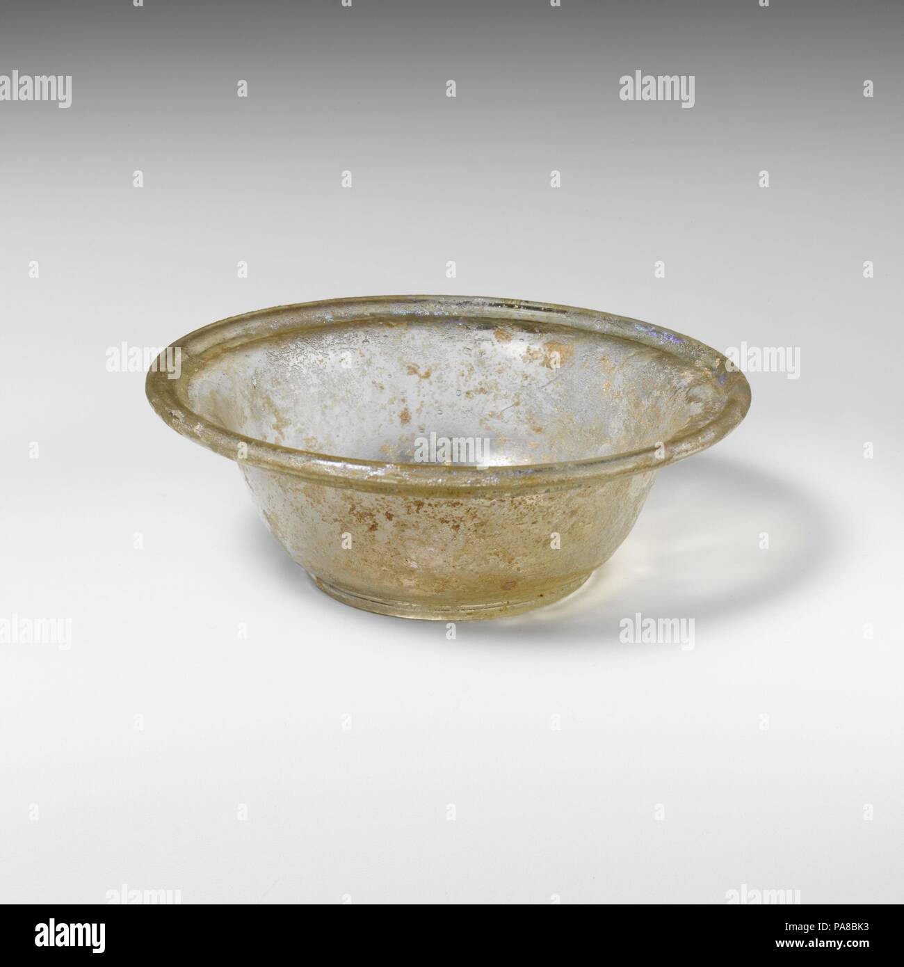Bol en verre. Culture : Roman. Dimensions : Diamètre : 4 3/16 in. × 2 1/16 in. (10,6 × 5,2 cm)Hauteur : 1 1/2 in. (3,8 cm). Date : 2ème-3ème siècle de notre ère. Incolore avec tingeOutsplayed verdâtre, horizontal, bord arrondi, rabattu et dans undercurve ; côtés sur le bas effilé ; anneau de base ; de profondeur, fond concave avec pontil cicatrice.intact ; bulles ; piqûre d'ébrécher, piqûres et irisés, avec de petites parcelles d'altération crémeuse. Musée : Metropolitan Museum of Art, New York, USA. Banque D'Images