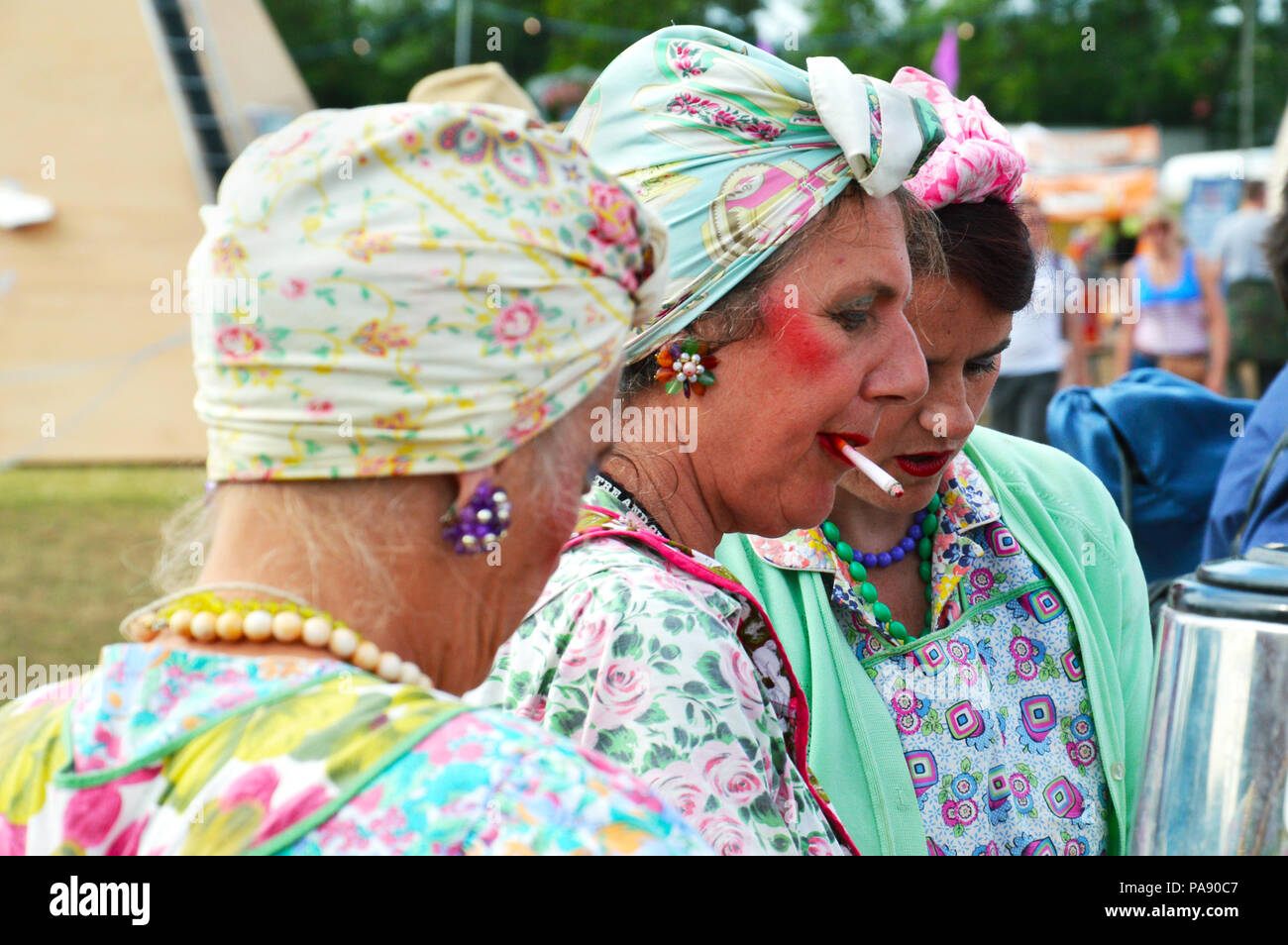 Mesdames habillés dans un style coloré milieu du 20ème siècle servant le thé au festival de Glastonbury. Banque D'Images