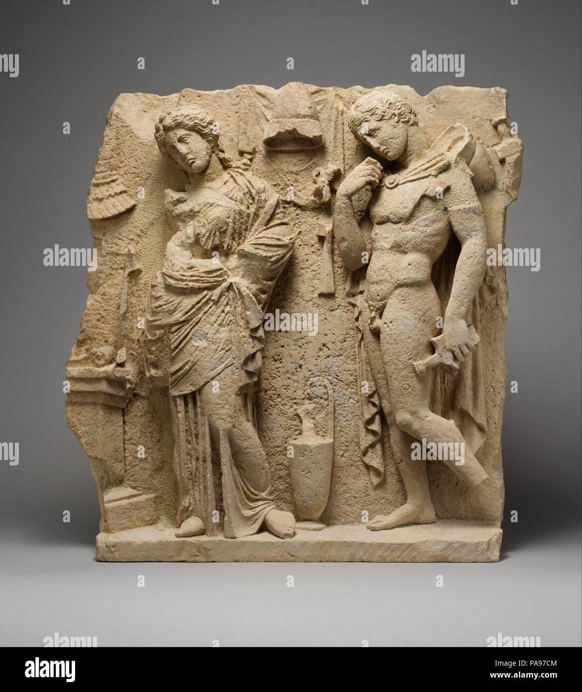 Relief funéraire en calcaire. Culture : le grec, l'italien, Tarentine". Dimensions : H. 23 1/16 in. (58,5 cm) ; largeur que les conserves de 21 1/8 in. (53,6 cm). Date : ca. 325-300 av. J.-C.. Tarente (Taranto) moderne était un riche colonie grecque sur la côte sud-est de l'Italie, un rôle central emplacement le long de la route commerciale entre la Grèce et l'Italie. Au cours du quatrième siècle avant J.-C., tombe ostentatoire monuments dans la forme de petits bâtiments, qui rappelle un temple décoré de sculptures peintes rempli la ville cimetière. Ce clapet doit venir d'un tel bâtiment. Il s'agit d'un jeune guerrier et une femme debout par un autel. Être Banque D'Images