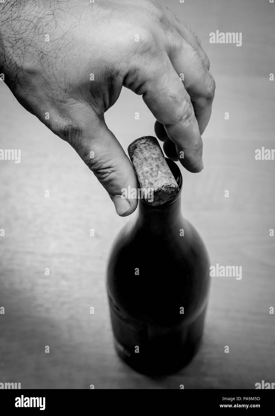 Photo en noir et blanc. Vue de dessus d'une bouteille de vin. La main d'un homme de mettre un bouchon sur la bouteille. Banque D'Images