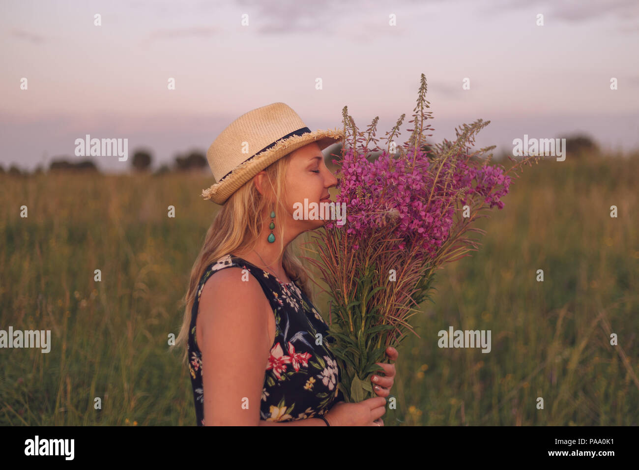 Jeune fille dans un champ de fleurs jouit de la nature au coucher du soleil. Banque D'Images