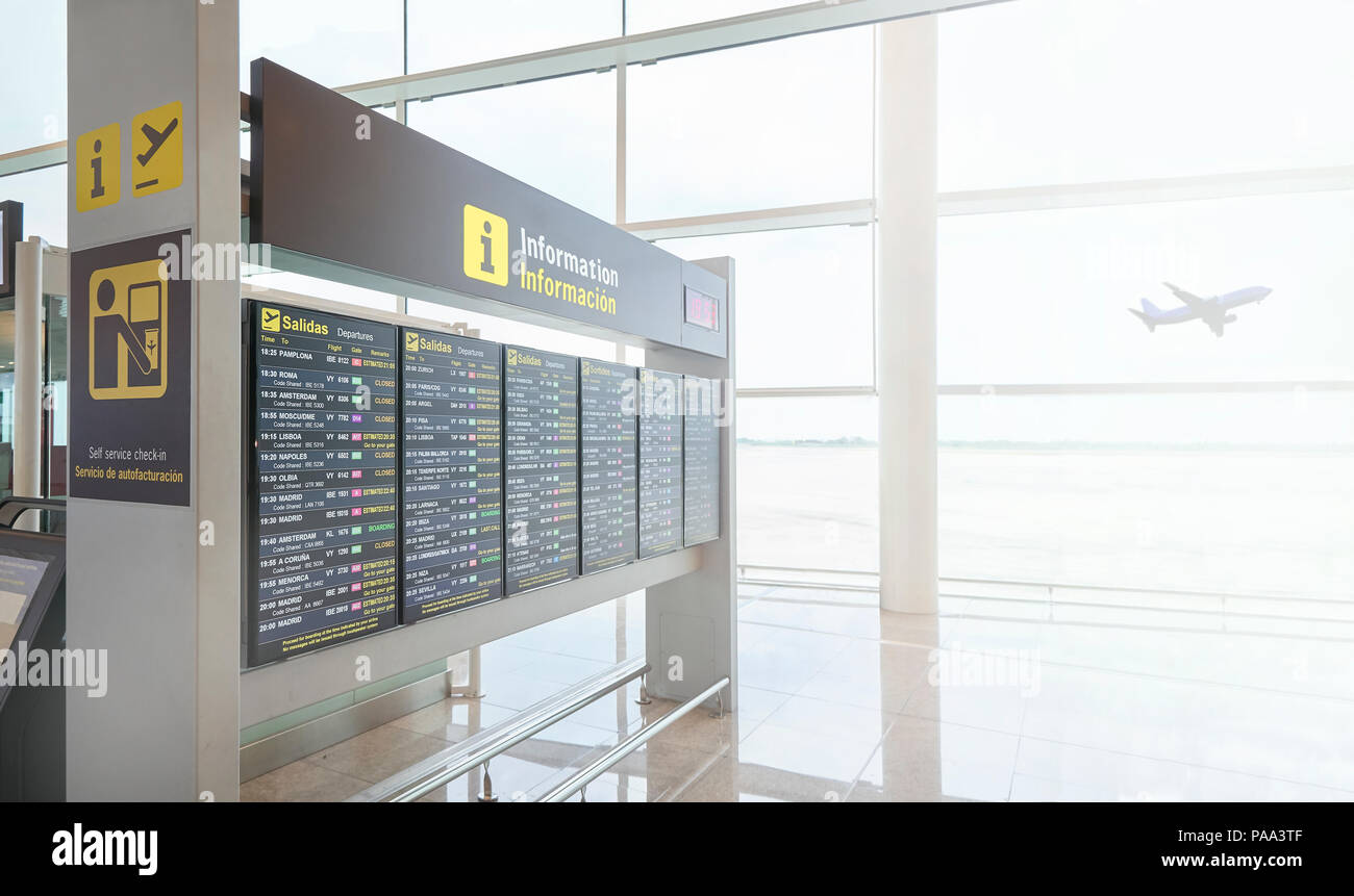 Un calendrier numérique afficher dans un aéroport européen de l'information et de départs des vols montrant un avion décollant en arrière-plan. Banque D'Images