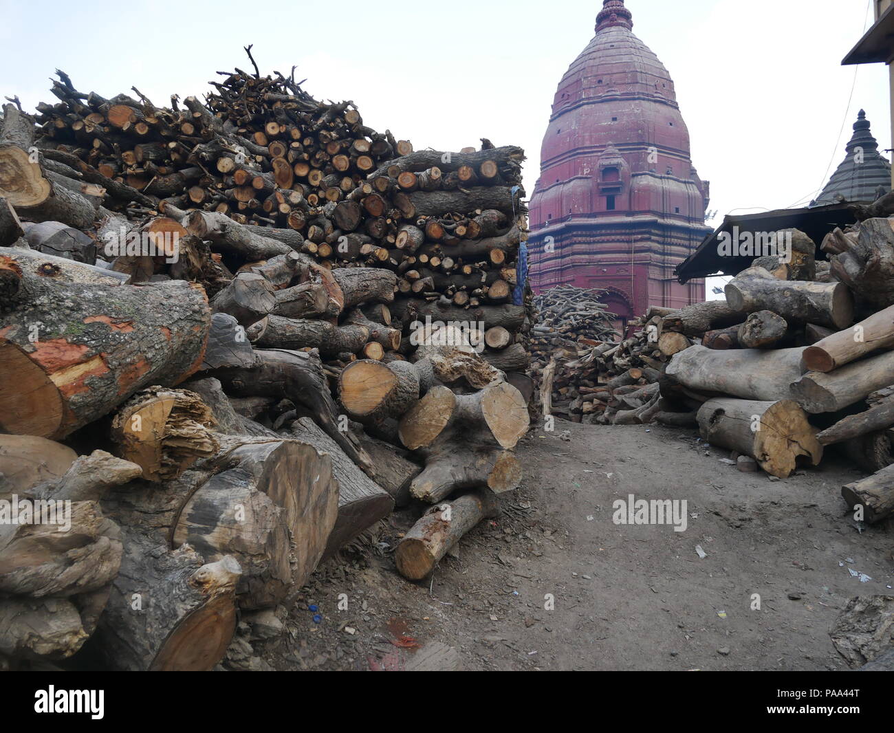 Corps en bois de manguier utilisé dans les rituels de gravure est empilé près d'un temple spire à Manakarnika Ghat, Varanasi, Inde. Banque D'Images Corps en bois de manguier utilisé dans les rituels de gravure est empilé près d'un temple spire à Manakarnika Ghat, Varanasi, Inde. Banque D'Images
