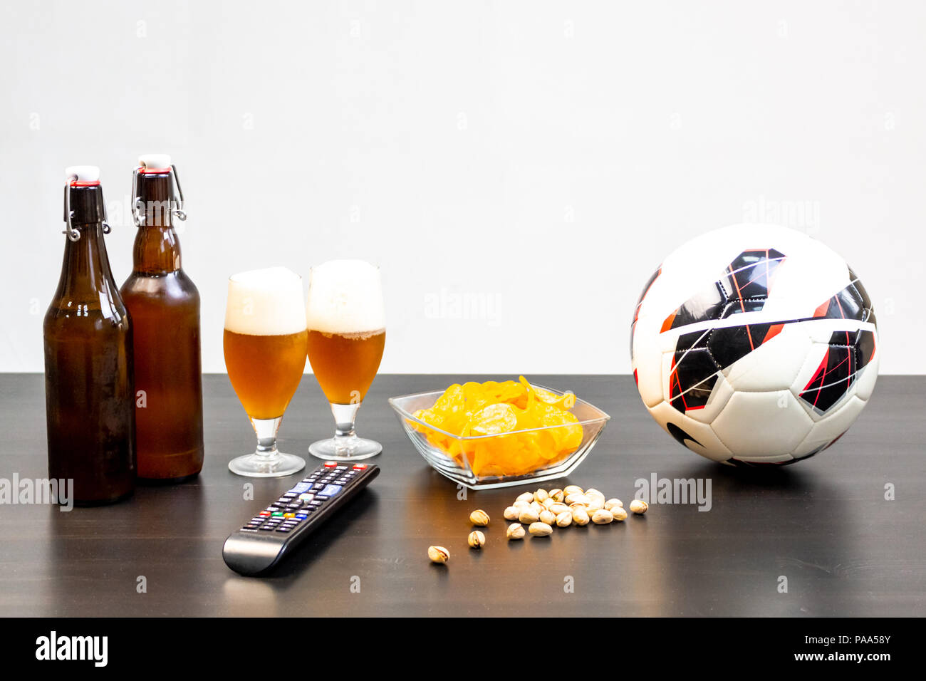 Les gens prêts à regarder le football à la télévision avec de la bière. Il y a la bière sur la table, la bille, TV, des collations. Bière artisanale. Fond clair. Banque D'Images