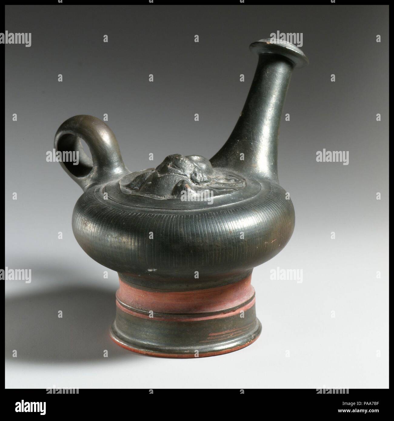 Guttus en terre cuite (flacon avec poignée et bec verticale). Culture : le grec, l'italien, le Campanien. Dimensions : 5 1/4''. (13.3cm). Date : 4ème siècle avant J.-C.. Sur le dessus, la tête d'Athéna, en relief. Musée : Metropolitan Museum of Art, New York, USA. Banque D'Images