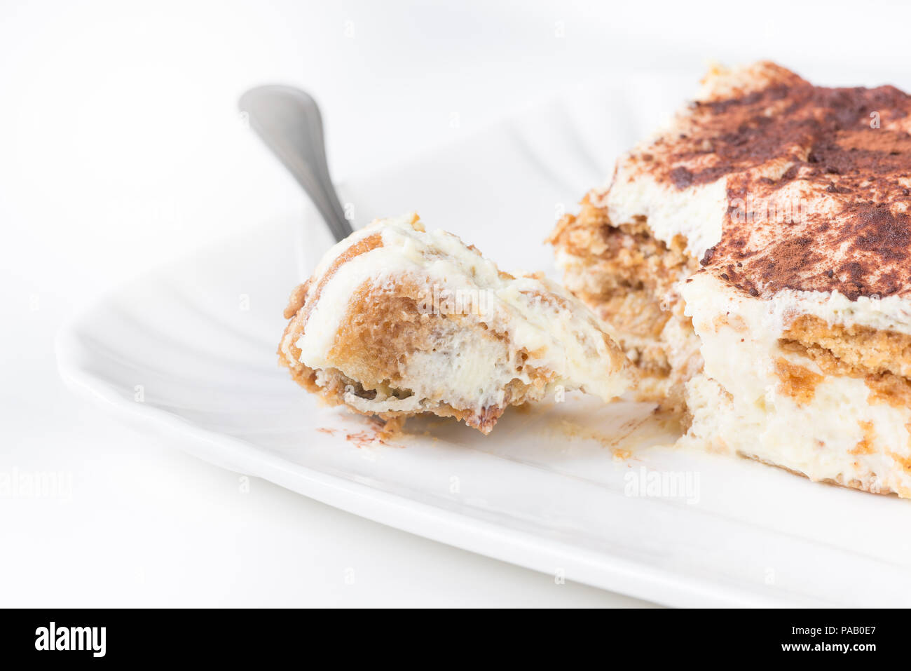 Tranche de Tiramisu fait maison sur une plaque, sur fond blanc, side view Banque D'Images