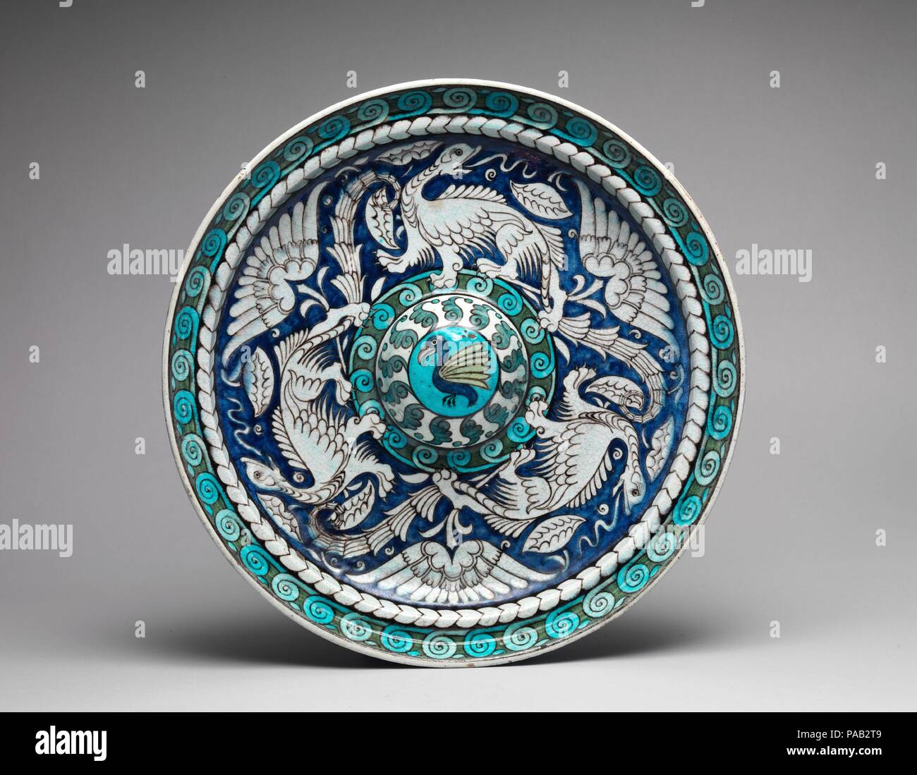 La plaque. Culture : British (Londres). Designer : William de Morgan (britannique, Londres 1839-1917 Londres). Dimensions : Diamètre : 16 in. x profondeur : 2 1/2 in. (40,6 x 6,4 cm). Fabricant : Fin des sables bitumineux (poterie) britannique. Date : ca. 1890-1907. Connu pour son style '' bleu turquoise et de céramiques inspirées par d'Iznik pottery, de Morgan produite avec du glaçage, plus doux plus riche de couleurs que ses contemporains. Particulièrement friands des dragons, il les a utilisées, la danse entre fleurs stylisées, d'ancrer cette conception. Assistant en chef Charles peint passager l'ornement à Fulham à Londres, où de Morgan propose ses oeuvres Banque D'Images
