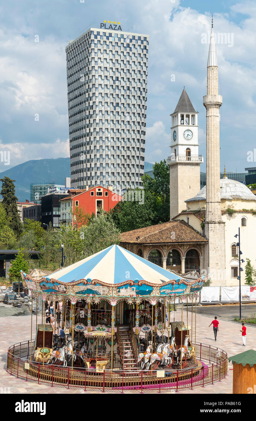 Un carrousel pour enfants dans la place Skanderbeg, avec la mosquée Et'hem Bey, la tour de l'horloge et la Plaza Hotel en arrière-plan, Tirana, Albanie, Banque D'Images