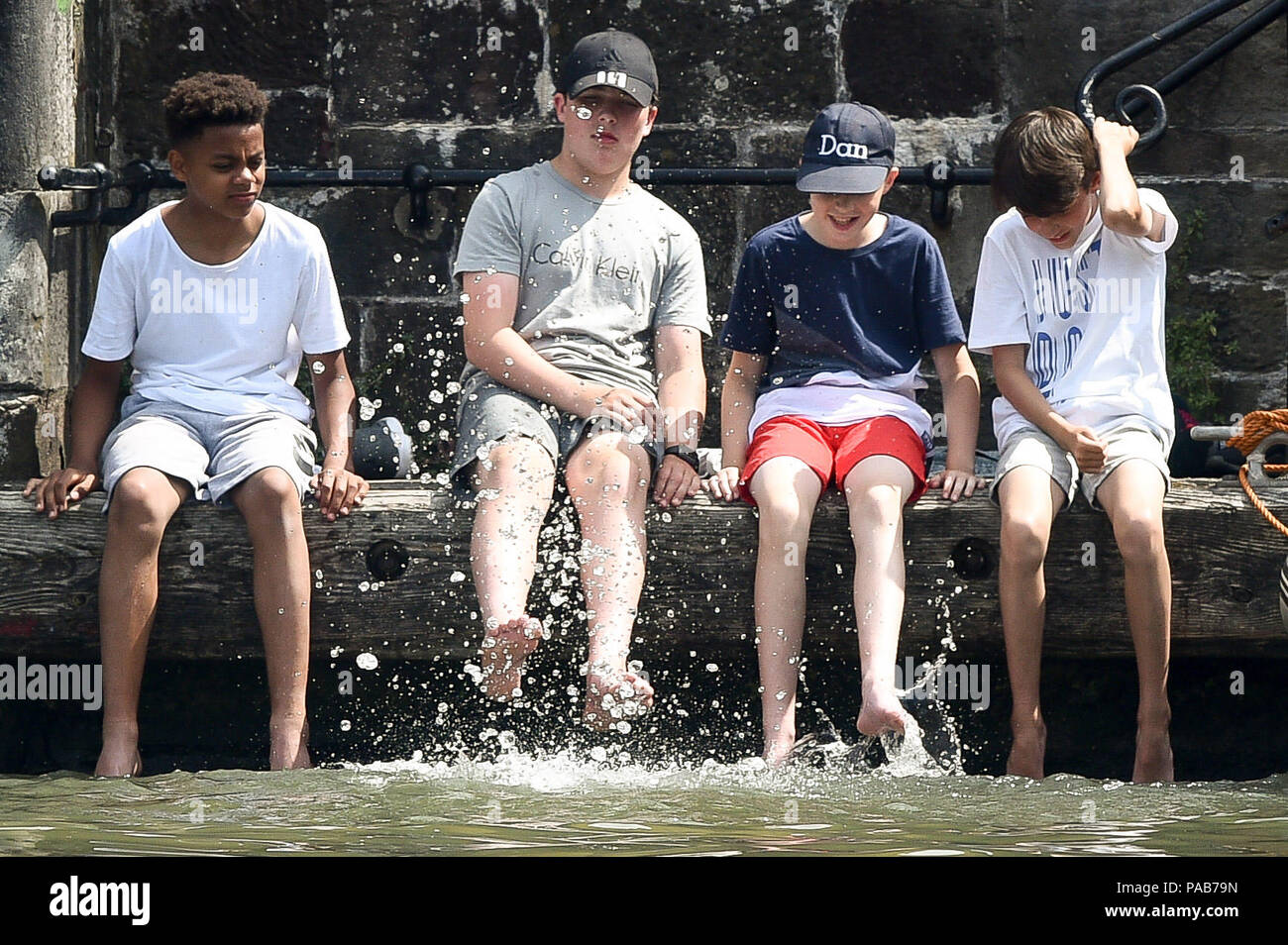 Les enfants s'amusent dans l'eau comme ils balancent leurs pieds dans le port flottant au cours de l'Harbour Festival dans le centre-ville durant les beaux jours. Banque D'Images