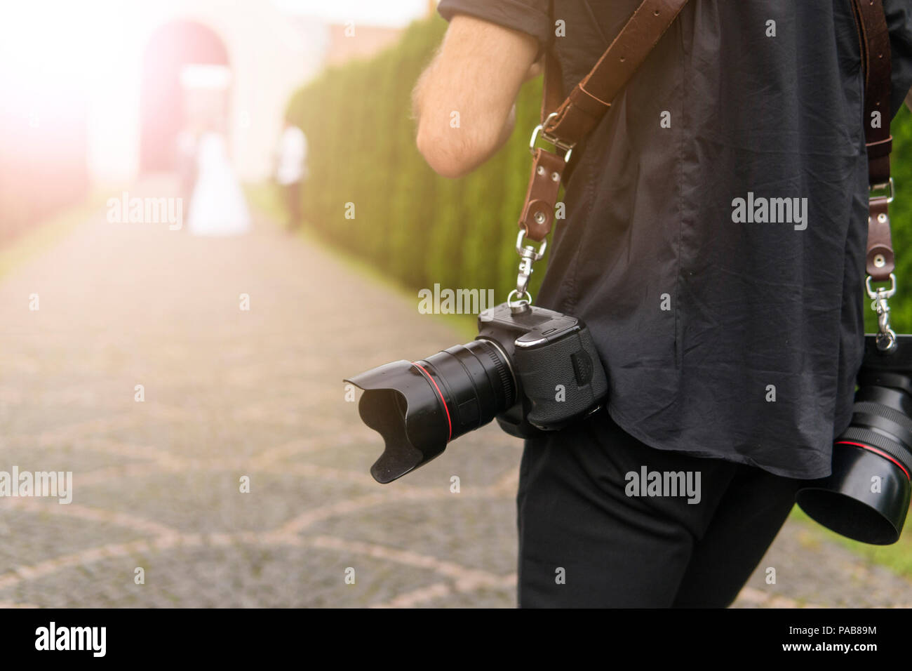 Photographe professionnel de mariage prend des photos des mariés dans le jardin, le photographe en action avec deux caméras sur un bretelles. Banque D'Images