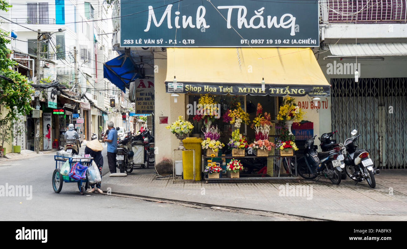 Vendeur de rue vietnamiens en face d'un fleuriste à Ho Chi Minh City, Vietnam. Banque D'Images