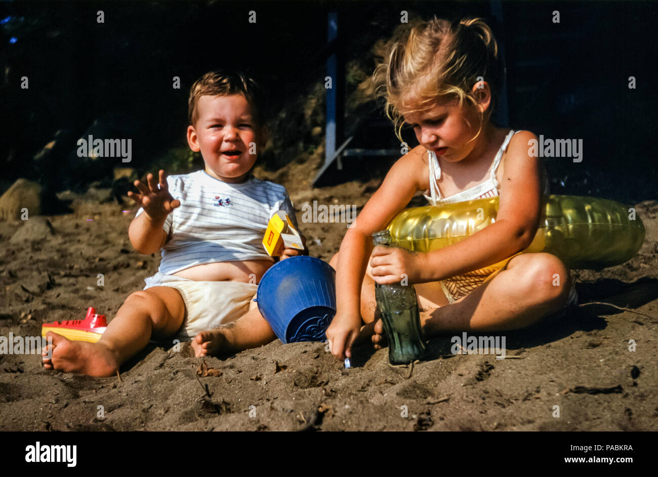 Jeune Fille Portant Un Maillot De Bain Et Anneau De Natation En Plastique Et Son Bebe Frere Dans Une Couche Ou Un Bebe Assis Jouant Sur Une Plage De Sable Avec Un