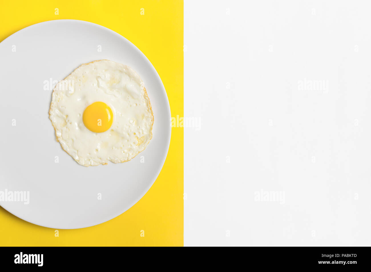 Œuf frit sur blanc plaque ronde avec split couleur jaune/blanc et fond copyspace. Banque D'Images