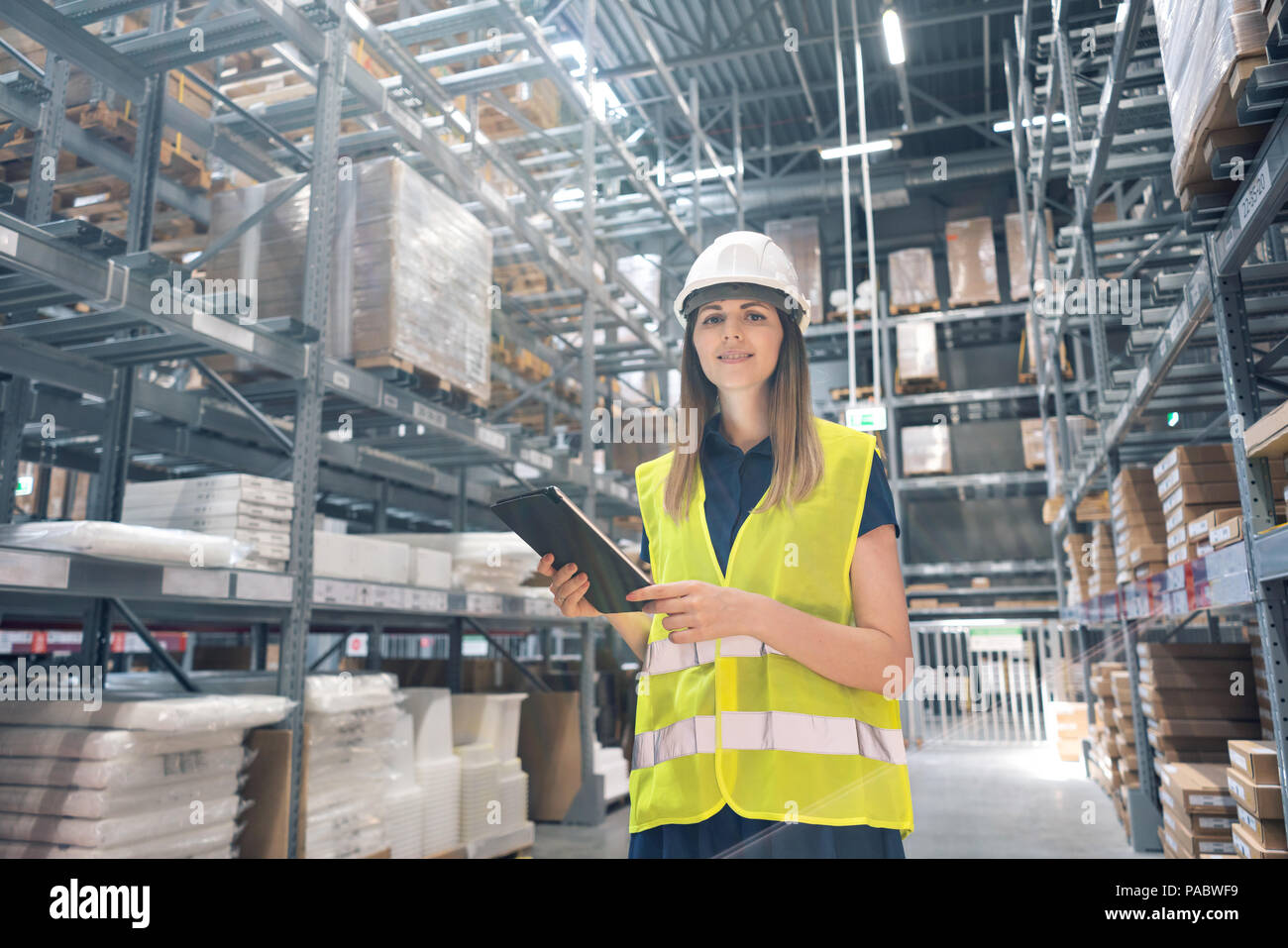 Belle jeune femme de magasin de meubles à centre commercial. Jeune fille à la recherche pour les produits d'une tablette est de vérifier les niveaux de stock dans un entrepôt. Concept logistique Banque D'Images