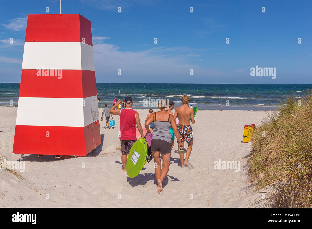 Les gens qui marchent dans le sable vers la mer rouge et un blanc d'une tour de sauvetage, Rorvig, Danemark, le 20 juillet 2018 Banque D'Images