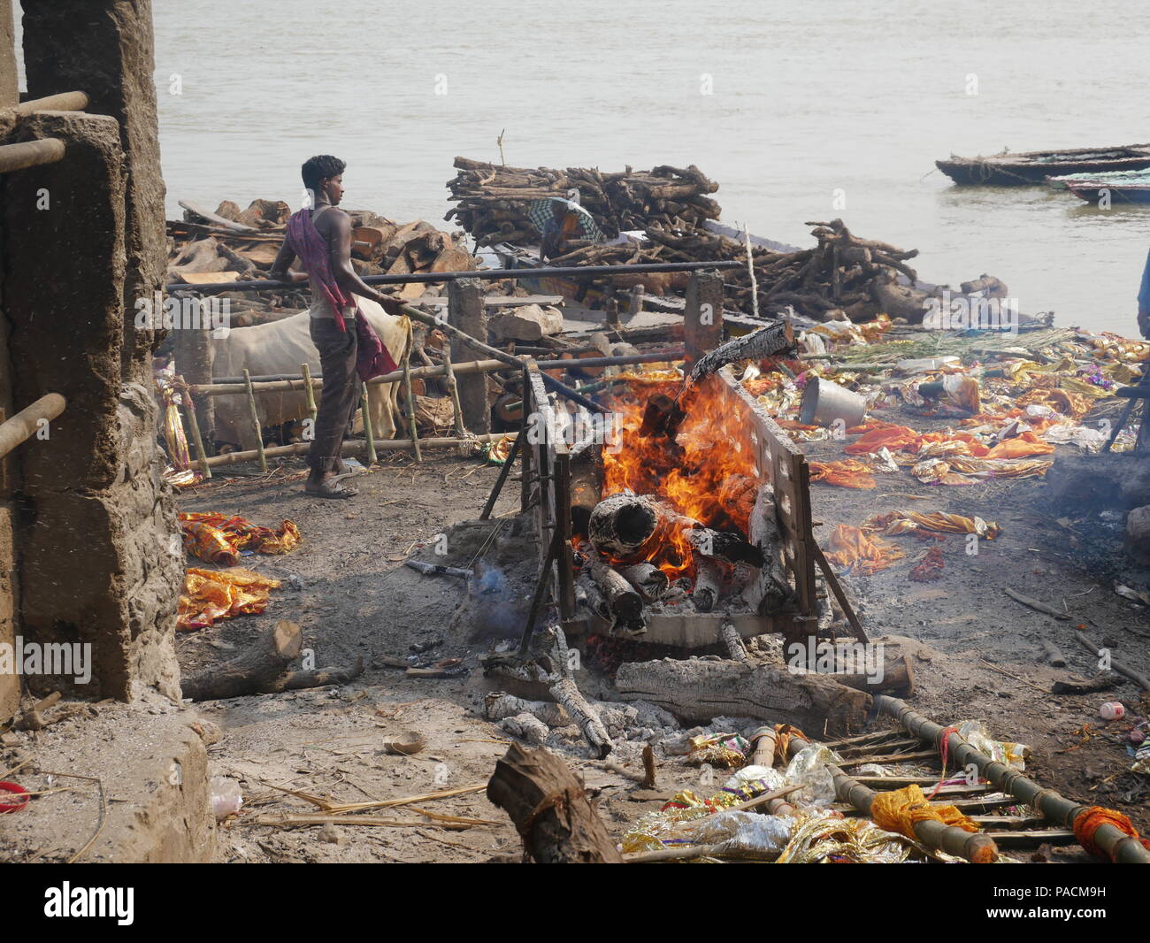 Un intouchable attise les braises d'une caisse en Manakarnika Ghats, Varanasi, Inde. Banque D'Images Un intouchable attise les braises d'une caisse en Manakarnika Ghats, Varanasi, Inde. Banque D'Images