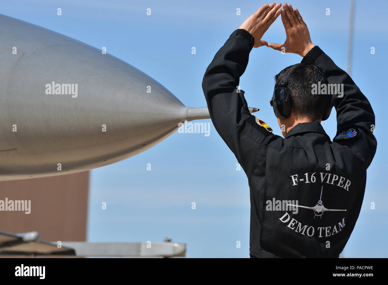 Un technicien de l'US Air Force marshale un Fighting Falcon F-16 affecté à l'équipe de démonstration Viper lors du cours de formation en vol Heritage 2016 à Davis-Monthan Air Force base, Arizona, le 4 mars 2016. Le F-16, un chasseur multirôle supersonique monomoteur propulsé par un turboréacteur Pratt & Whitney F100-PW-200/220 à postcombustion, est préparé pour des vols de démonstration afin d'afficher précision, maniabilité et capacités de combat lors de spectacles aériens et d'événements Heritage Flight. Banque D'Images