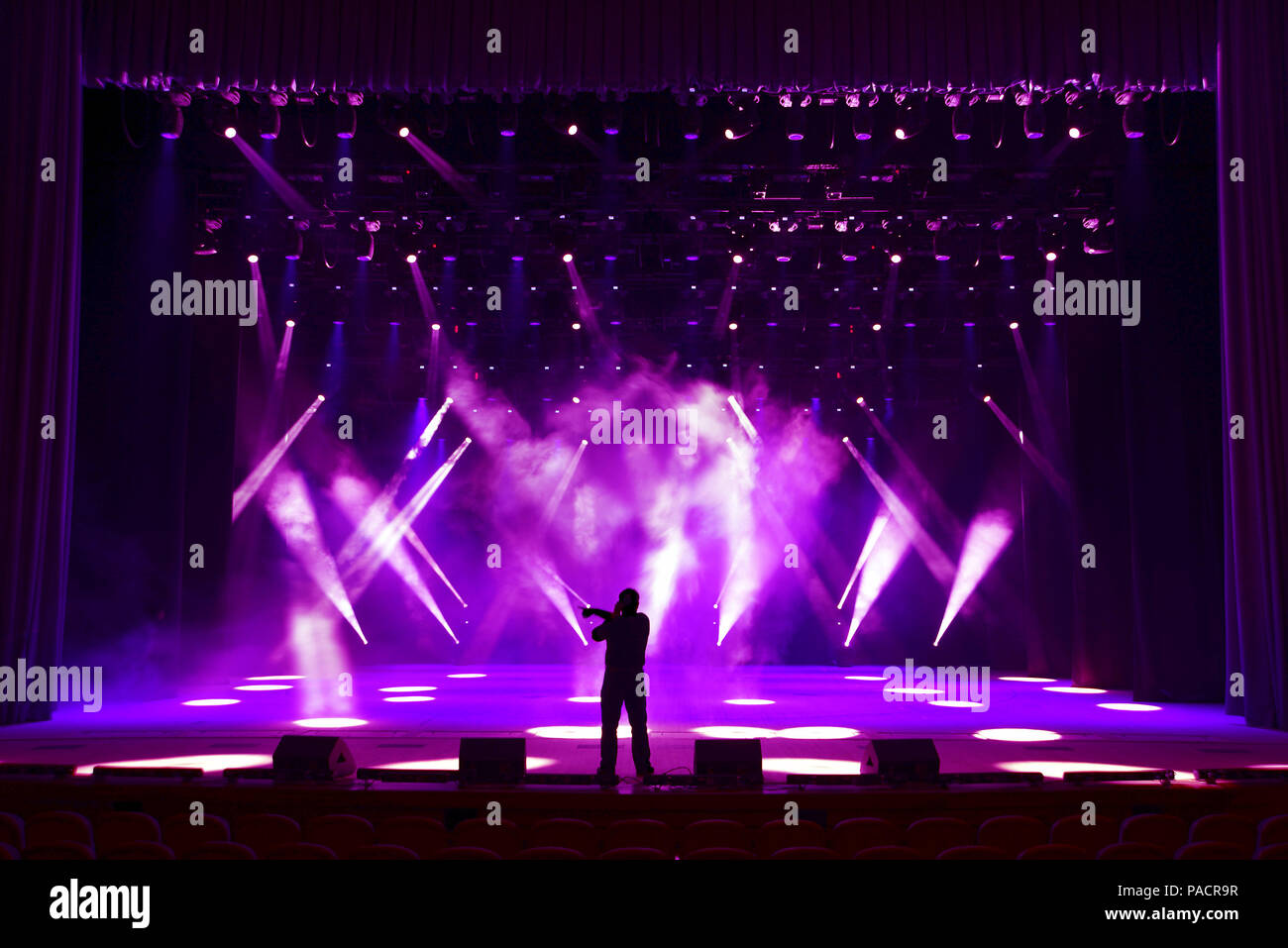 La silhouette de l'homme chanter sur une scène show lumineux sur fond de rayons de soffites et brouillard scénique Banque D'Images