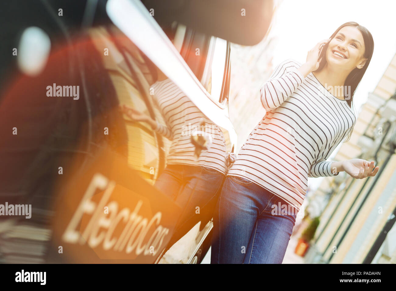 Femme souriante avec un téléphone à l'extérieur de la voiture Banque D'Images