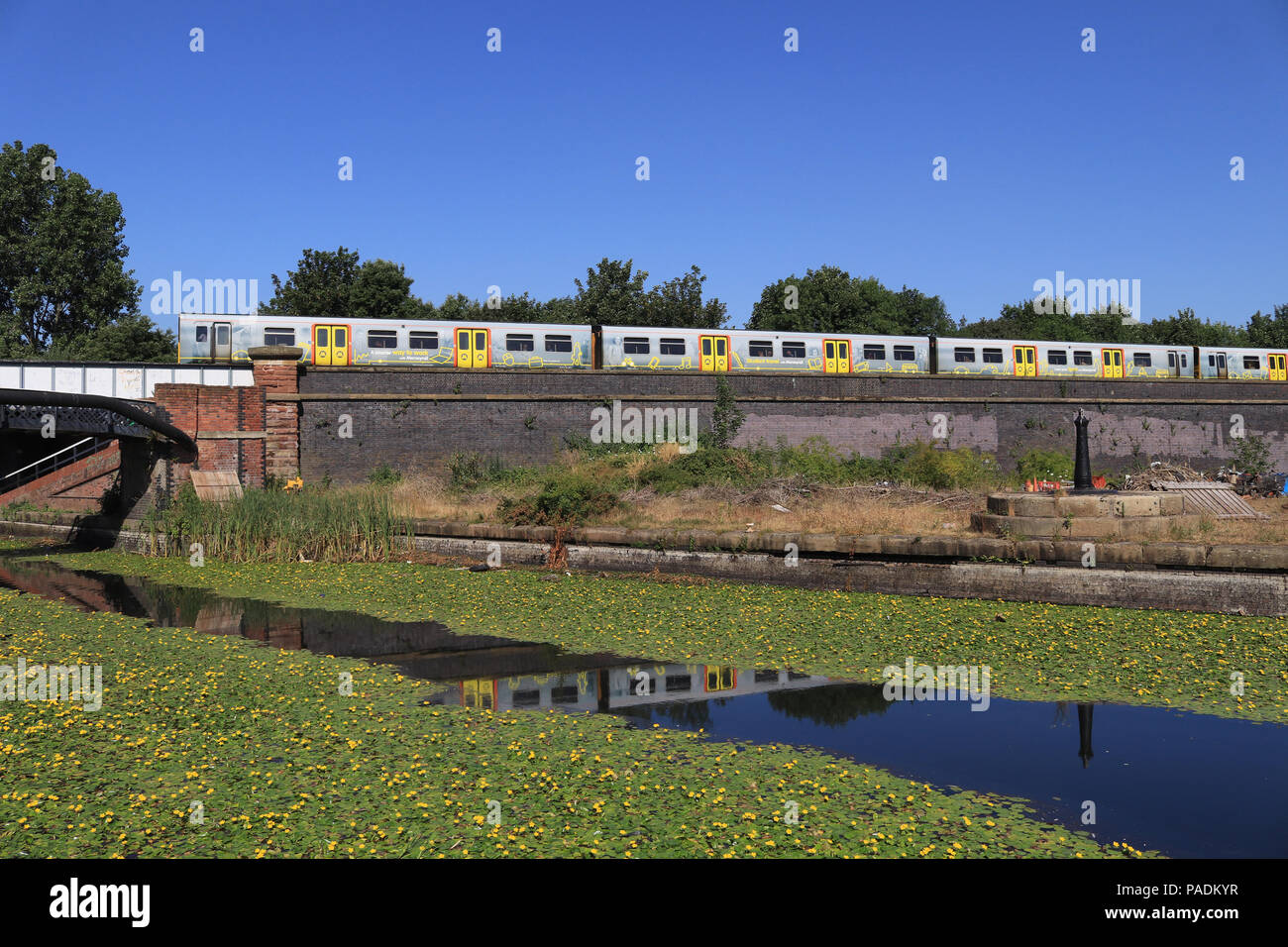 Un train roulant ferroviaire Mersey Liverpool à Southport traverse la Leeds et Liverpool canal près de la passerelle de la rue Caroline à Bootle. Banque D'Images