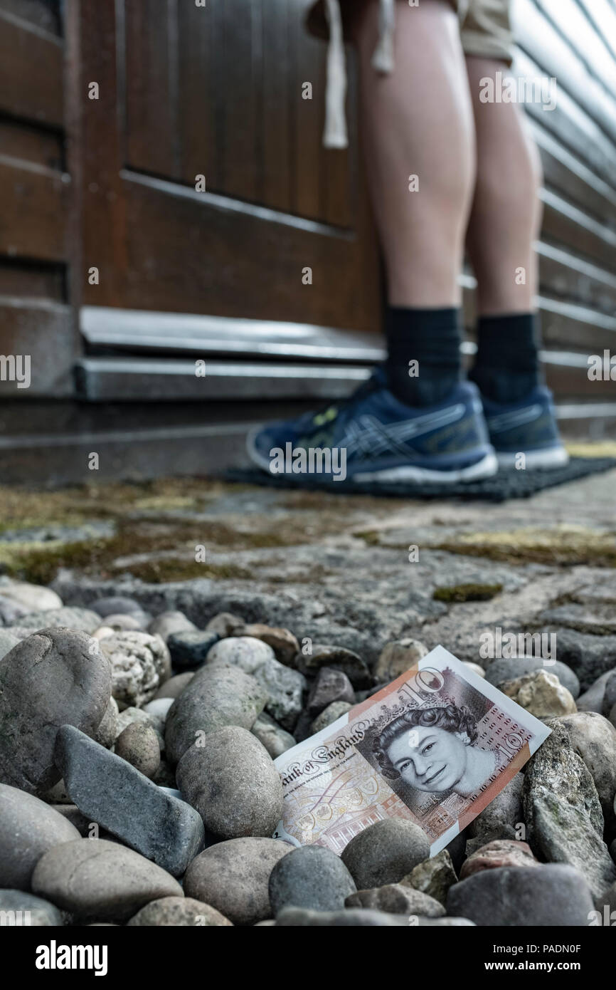 L'argent sous forme d'un billet de banque sur le sol à l'extérieur d'une maison. Banque D'Images