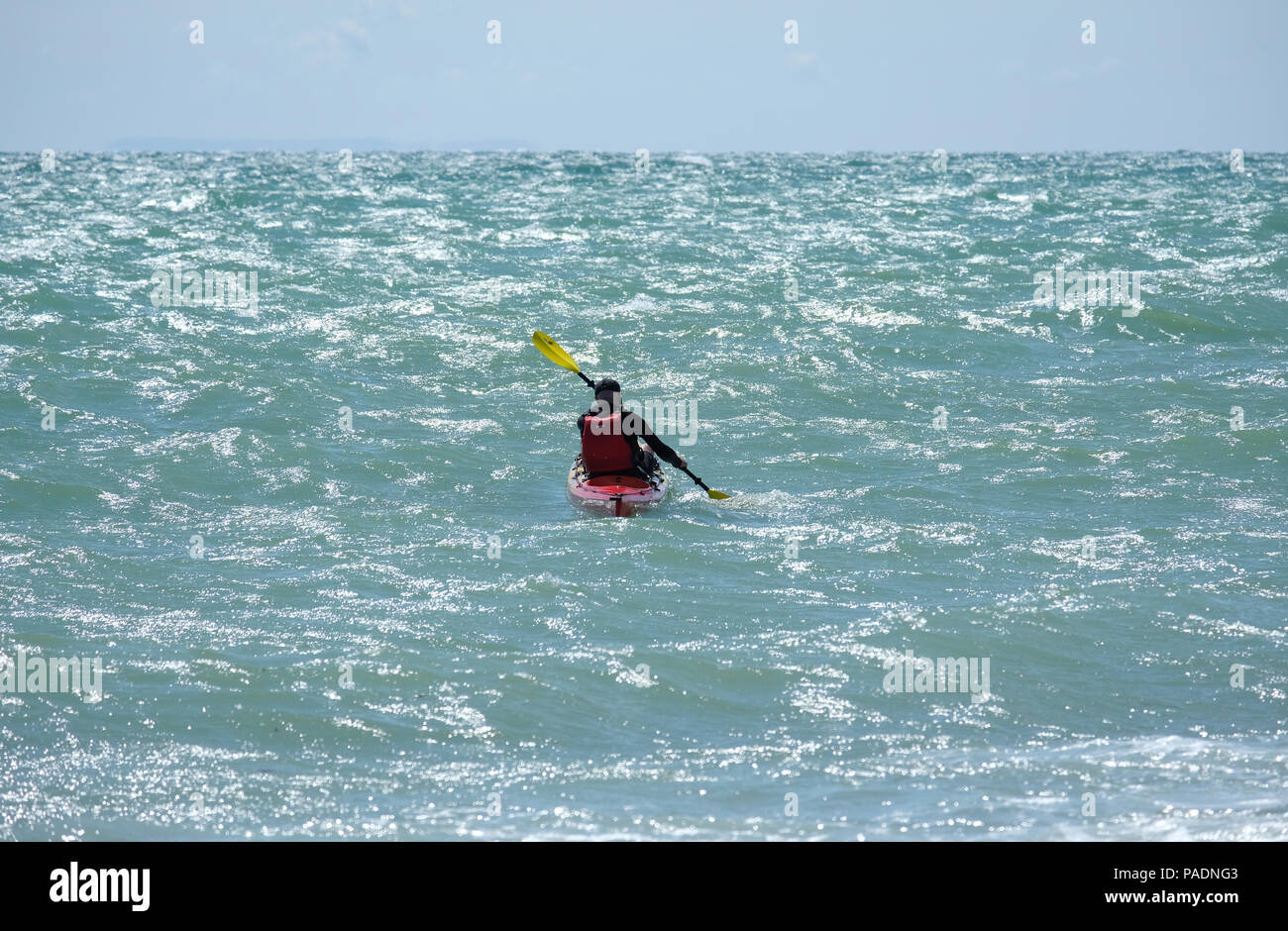 Homme portant un gilet de pagayage son kayak en mer agitée au large de la côte d'East Preston, West Sussex, UK. Direction l'Est vers l'Ouest. Banque D'Images