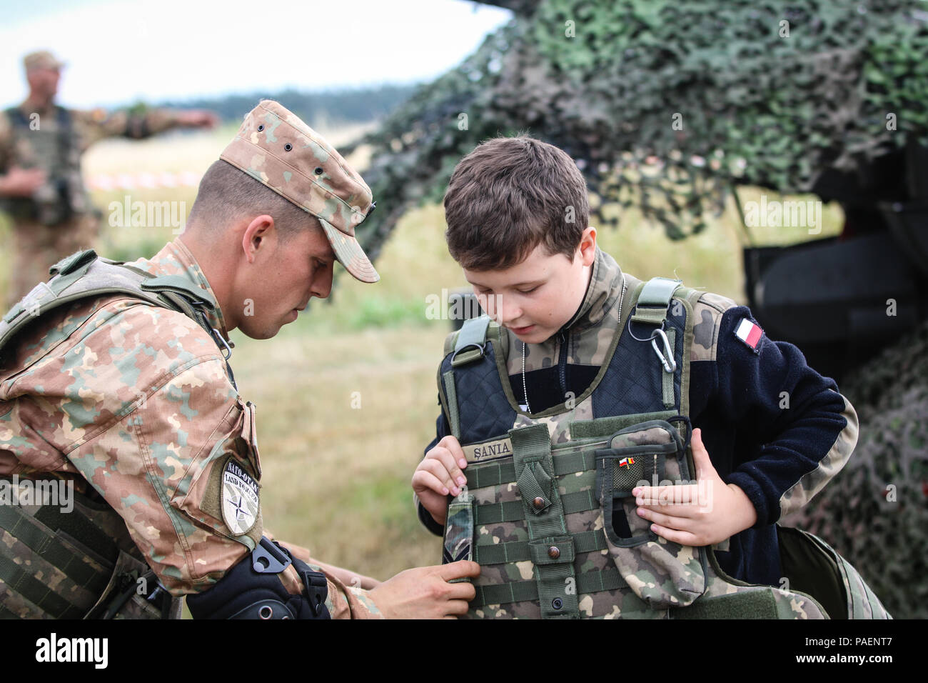 L'unité d'artillerie de défense aérienne roumaine connue sous le nom de Scorpions bleus participe à une exposition statique lors de la célébration du jour des chars de la 15e brigade mécanisée avec le groupement tactique Pologne à Orzysz, en Pologne, le 14 juillet 2018. Un enfant essaie de l'équipement militaire pendant la manifestation publique soutenant la présence avancée renforcée de l'OTAN. L'image d'archives documente l'engagement de la communauté lors d'une exposition militaire. Banque D'Images