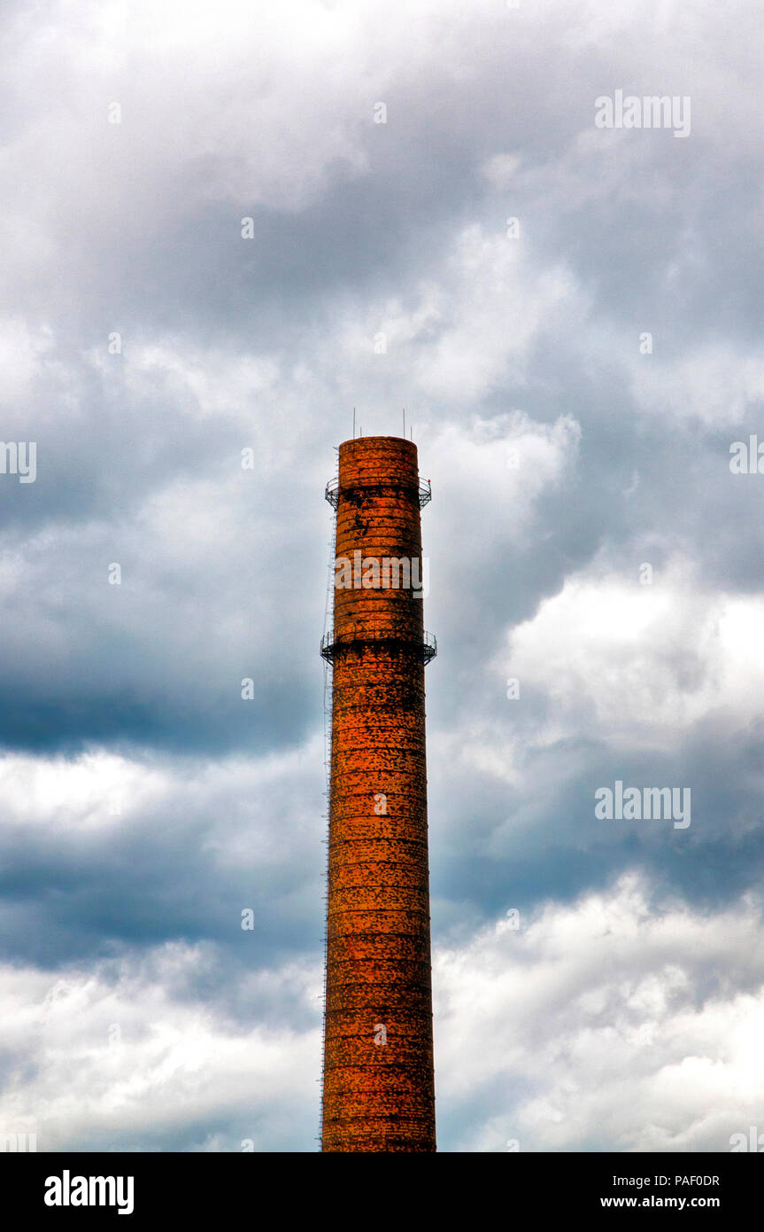 Vieille brique cheminée industrielle entourée d'un ciel dramatique Banque D'Images