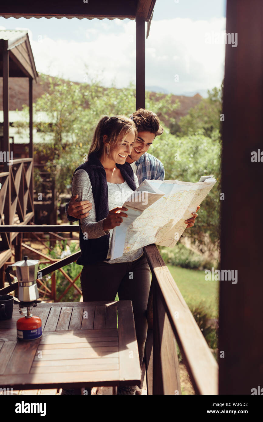 Couple debout dans leur chambre d'hôtel balcon et regarder la carte. L'homme et la femme reading map pour trouver de l'attraction touristique la plus proche. Banque D'Images