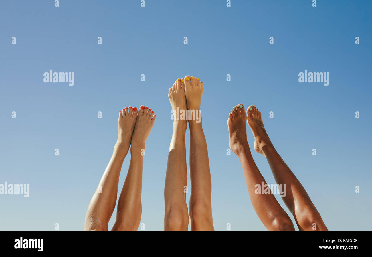 Close up de trois paire de jambes de jeunes femmes a augmenté vers le haut vers le ciel avec ciel bleu clair à l'arrière-plan. Banque D'Images
