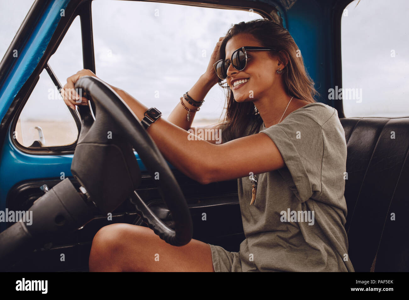 Portrait of happy young woman, conduire un camion. Smiling woman going on a road trip sur une vieille voiture. Banque D'Images