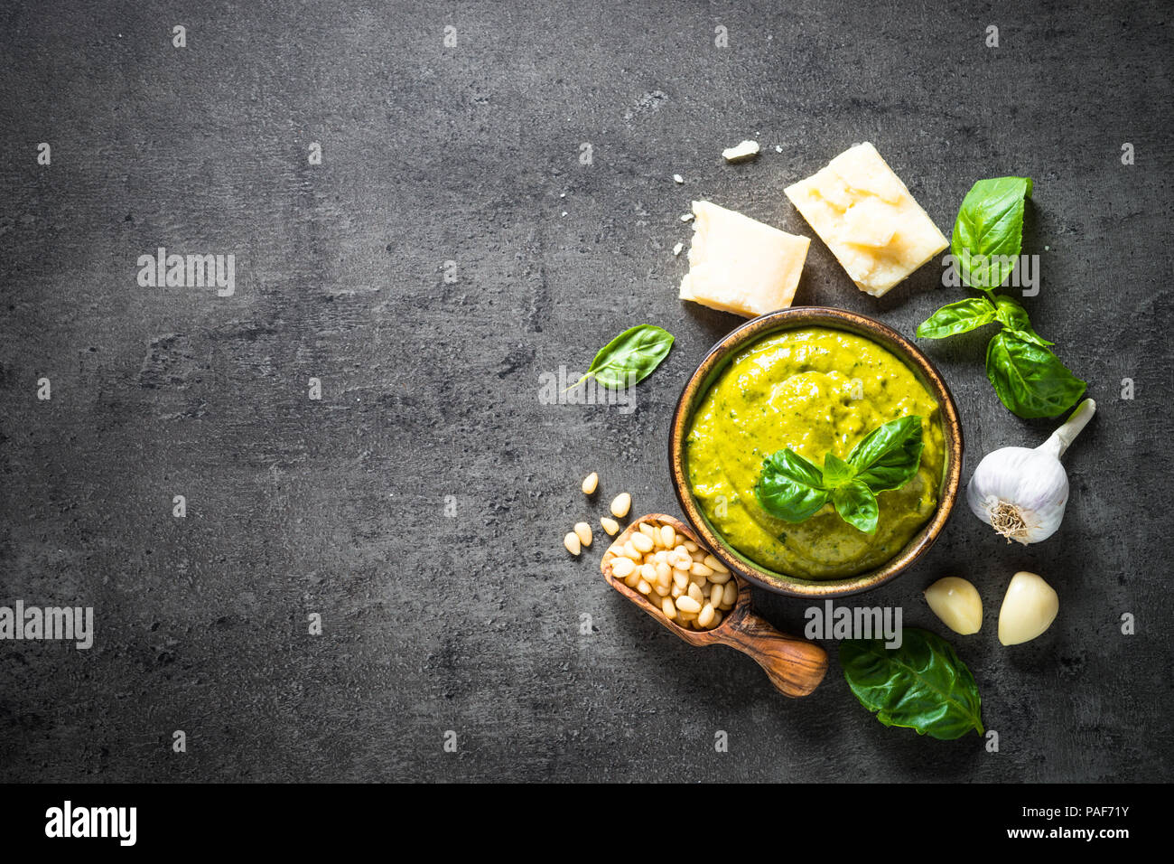 Sauce pesto avec des ingrédients sur pierre sombre tableau. Banque D'Images