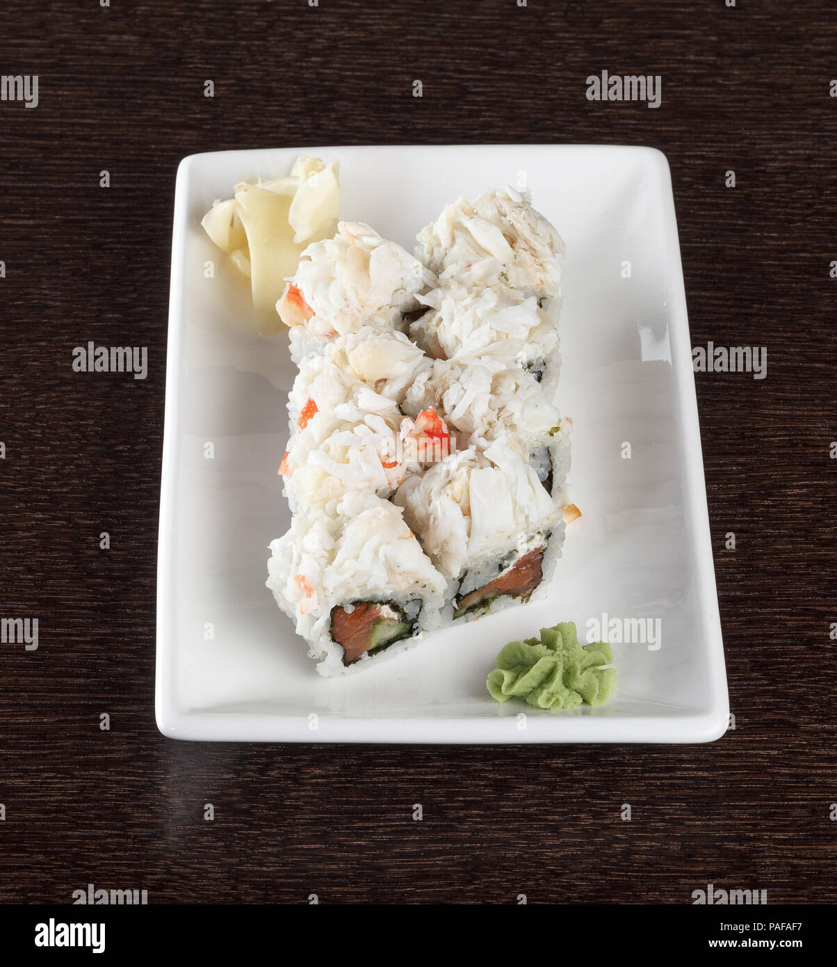 Rouleaux de sushi avec du saumon et la chair de crabe sur une plaque sur une table en bois. Vue de côté. Banque D'Images