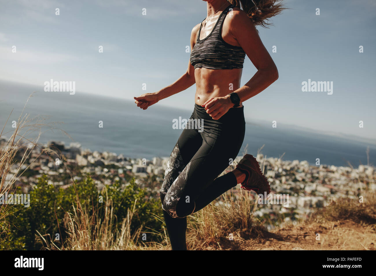 Sprint femme en bonne santé plus de sentier de montagne. Femme faisant courir entraînement sur chemin sur la colline parlementaire. Cropped shot. Banque D'Images