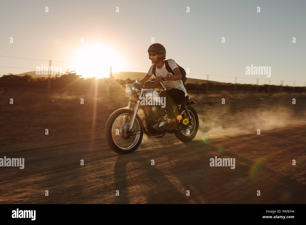 Jeune homme monté sur une moto vintage hors-route. Rider rouler à vélo très rapide sur route de campagne. Banque D'Images