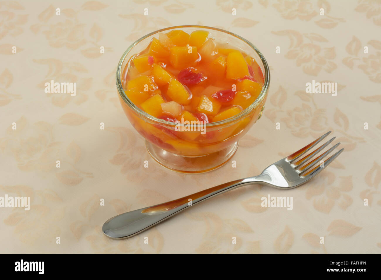 Cocktail de fruits en conserve dans du verre dessert fruit cup avec la fourchette sur la nappe Banque D'Images