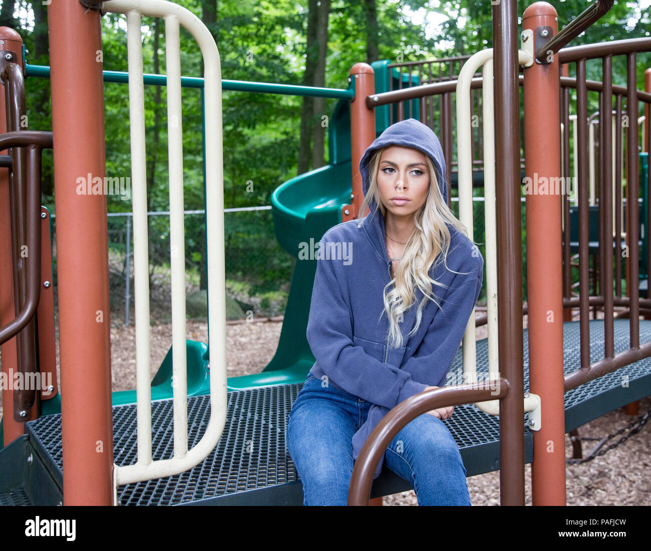 Teenage girl sitting à une aire de jeux dans une humeur maussade Banque D'Images