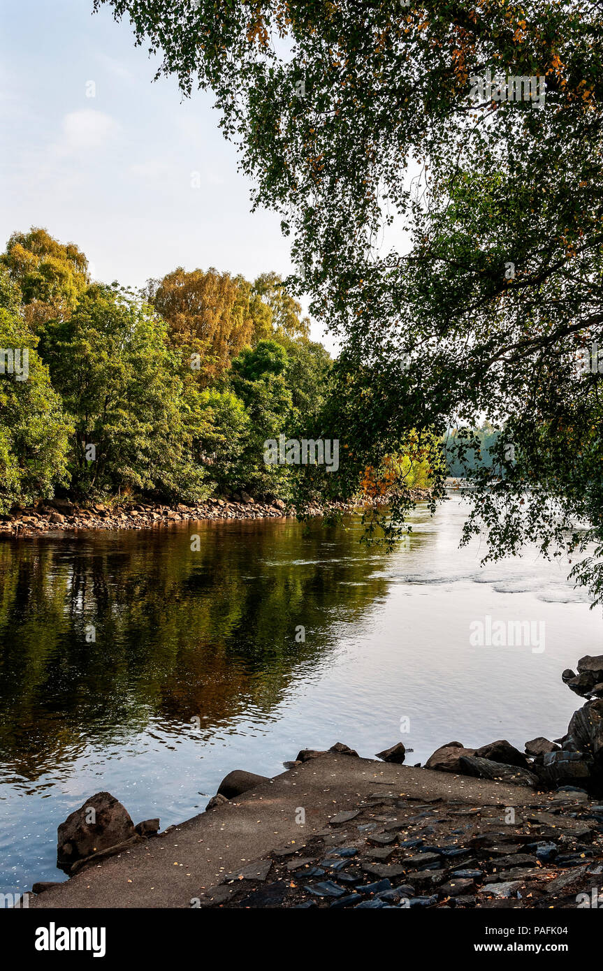 La rivière Tummel coule d'un sedately rock misty bend entre banques couvert à partir de laquelle les arbres avec leurs reflets dans le soleil d'automne Banque D'Images