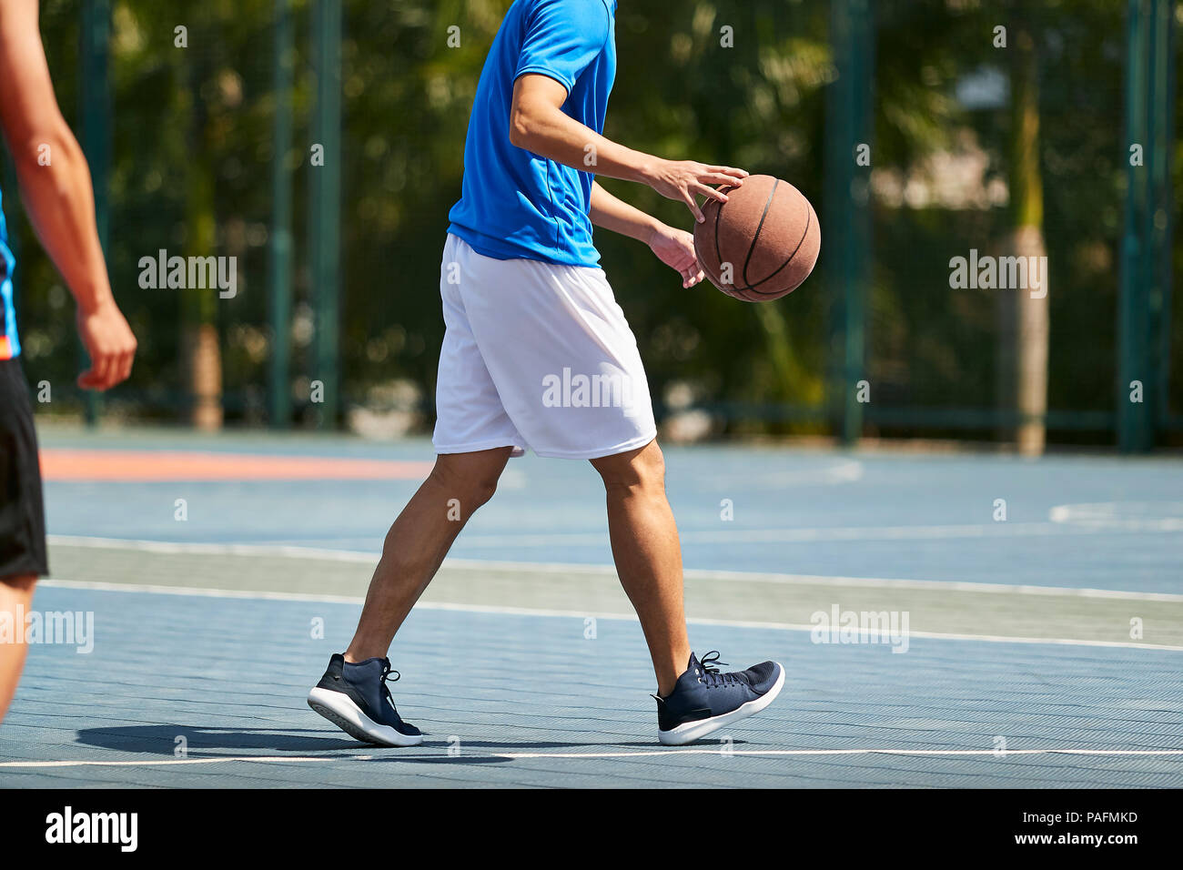 Les jeunes adultes asiatiques jouant au basket-ball à l'extérieur sur cour Banque D'Images