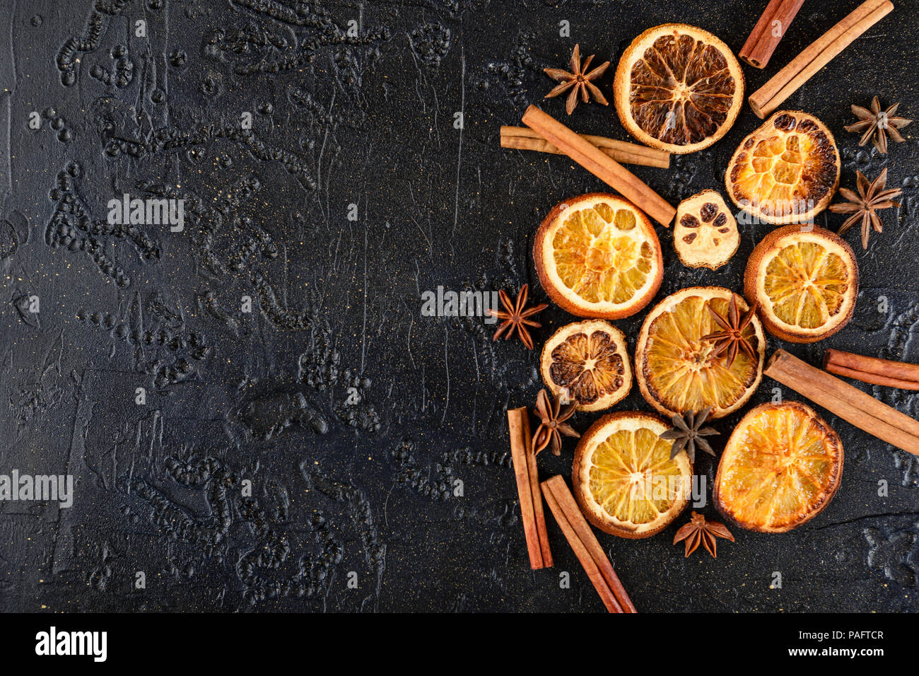 Fond noir avec des tranches d'orange séchées, des bâtons de cannelle et anis étoile Banque D'Images