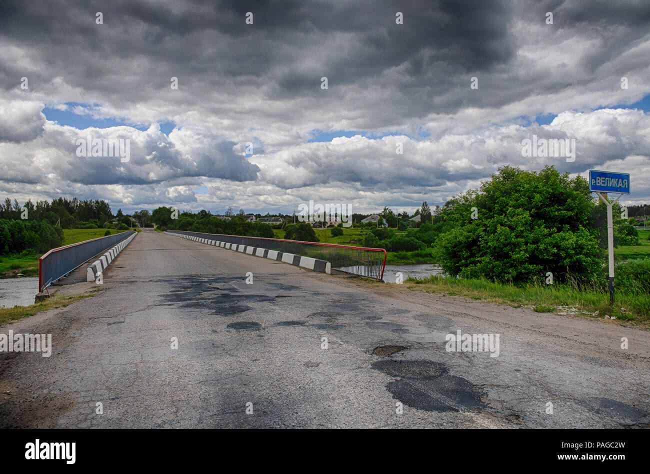 Paysage d'été avec ciel dramatique et pont sur la rivière Velikaya dans la région de Pskov (Russie) Banque D'Images