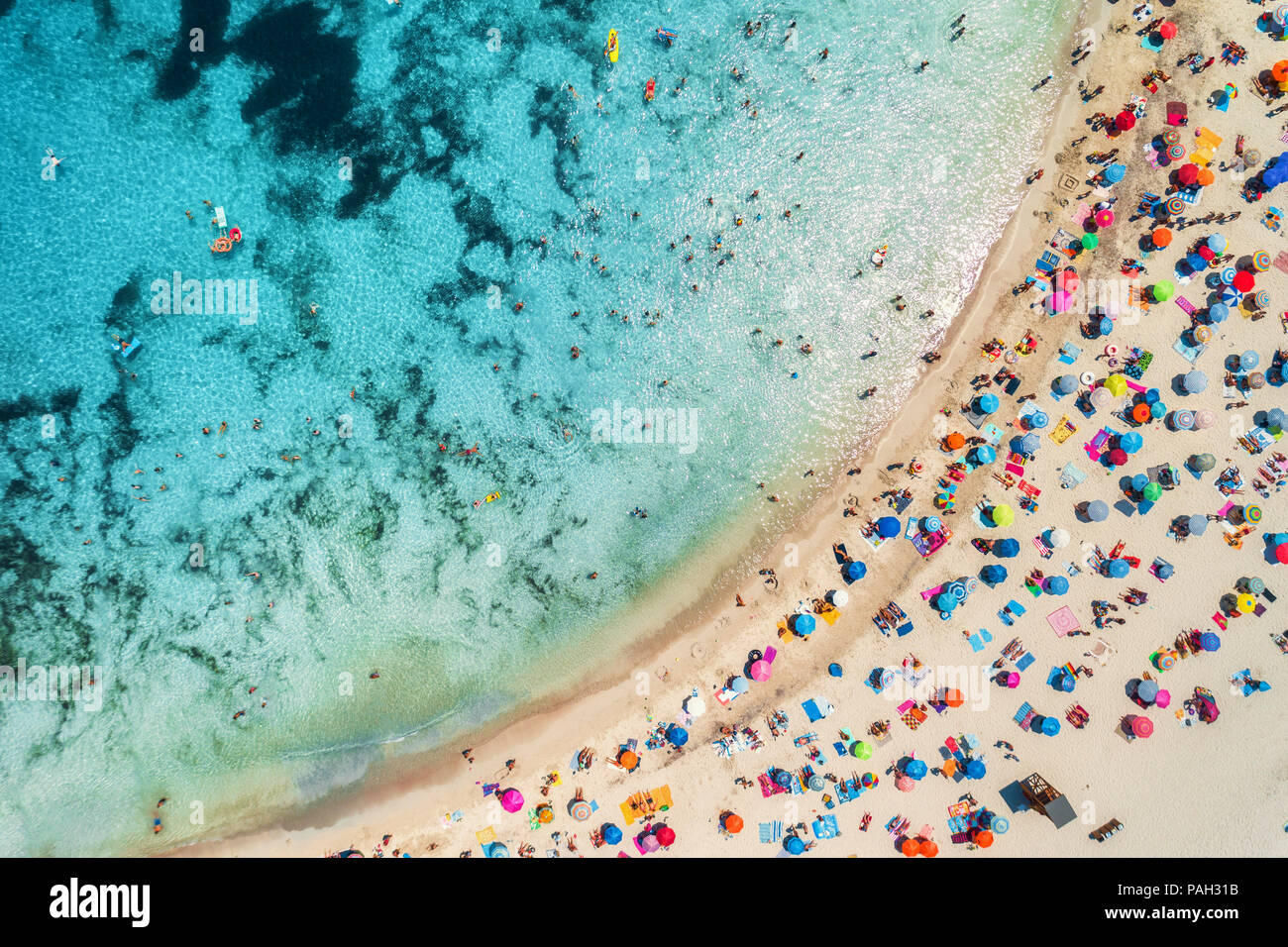 Vue aérienne de la plage de sable fin avec parasols colorés, d'une personnes dans la baie de la mer avec de l'eau d'un bleu transparent en matinée ensoleillée en été. En voyage Mallo Banque D'Images