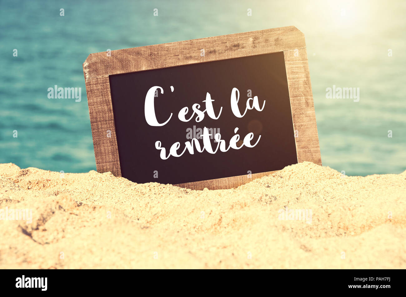 C'est la rentrée (sens Retour à l'école en français) écrit sur un tableau noir vintage dans le sable d'une plage Banque D'Images