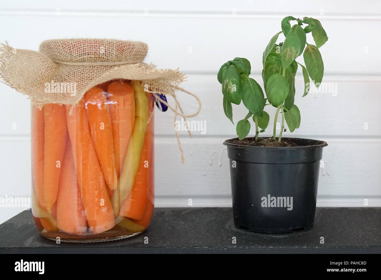 Pot en verre avec carottes et pot de fleur sur le plateau en bois Banque D'Images