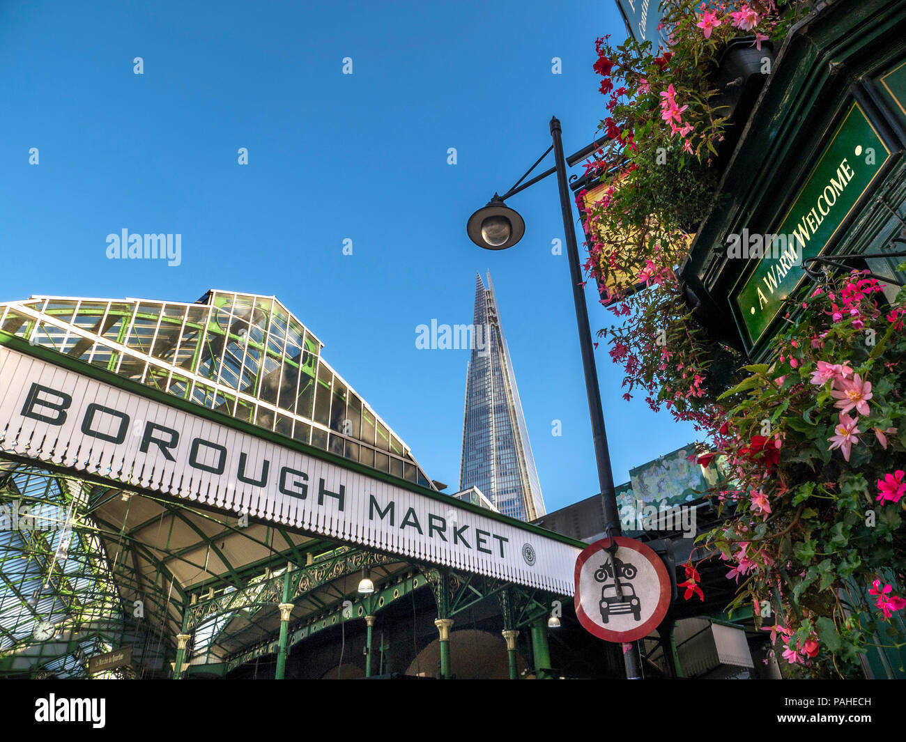 Fleurs extérieures de la façade du marché d'arrondissement et London Shard avec fleurs « The Market porter Pub » avec panneau « a Warm Welcome » au-dessus de l'entrée. Vue extérieure marché international des produits avec le Shard derrière le pont de Londres Southwark Londres Royaume-Uni Banque D'Images