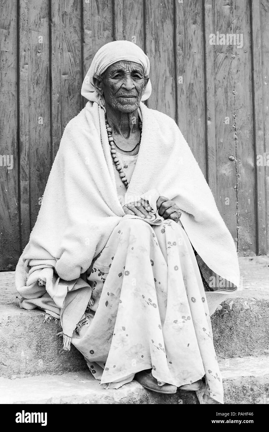 L'Éthiopie, d'Axoum - 24 septembre 2011 : belle femme éthiopienne non identifiés en tissu blanc est assis dans le portique de la maison. Les gens souffrent en Ethiopie Banque D'Images