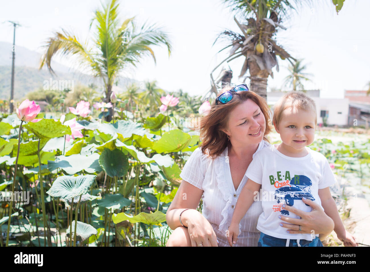 Mère et fils embrasser et rire à la rive du lac avec des lotus. Banque D'Images