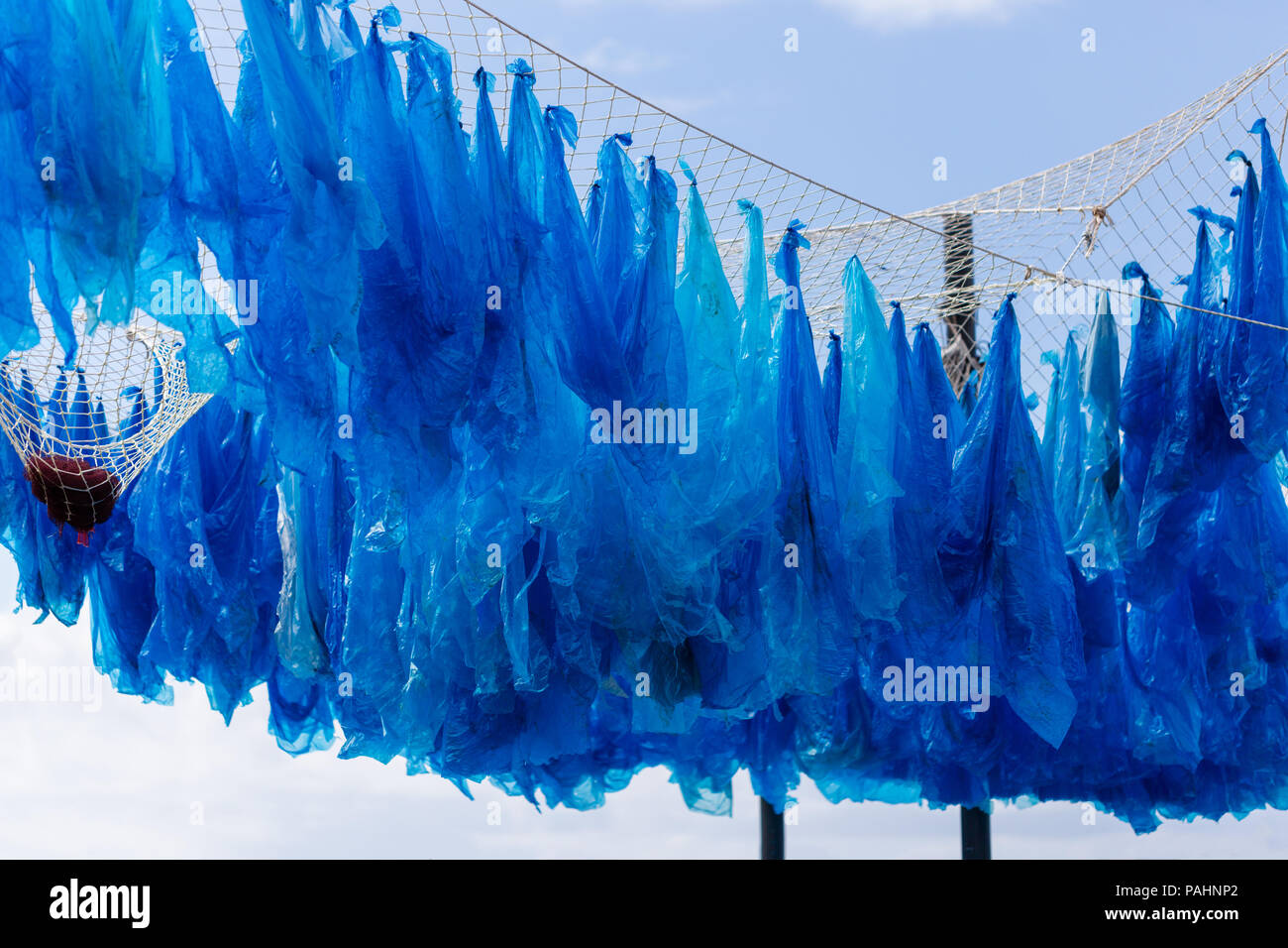 L'exposition de sensibilisation sur la menace à l'environnement marin. Sacs en plastique sont accrochés sur filet de pêche. Banque D'Images